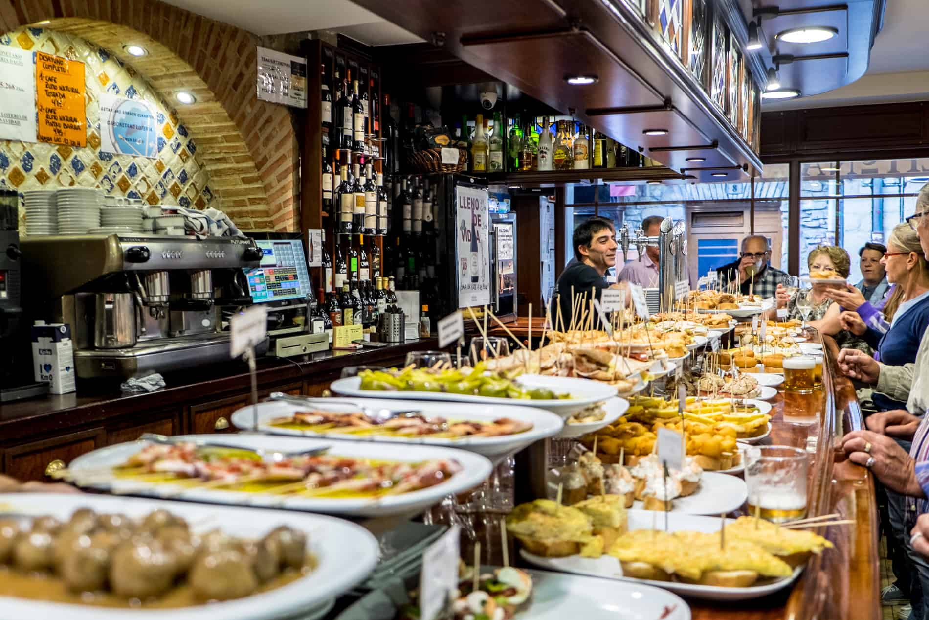 People stand at a bar in San Sebastian to eat bar snacks called Pintxos. 