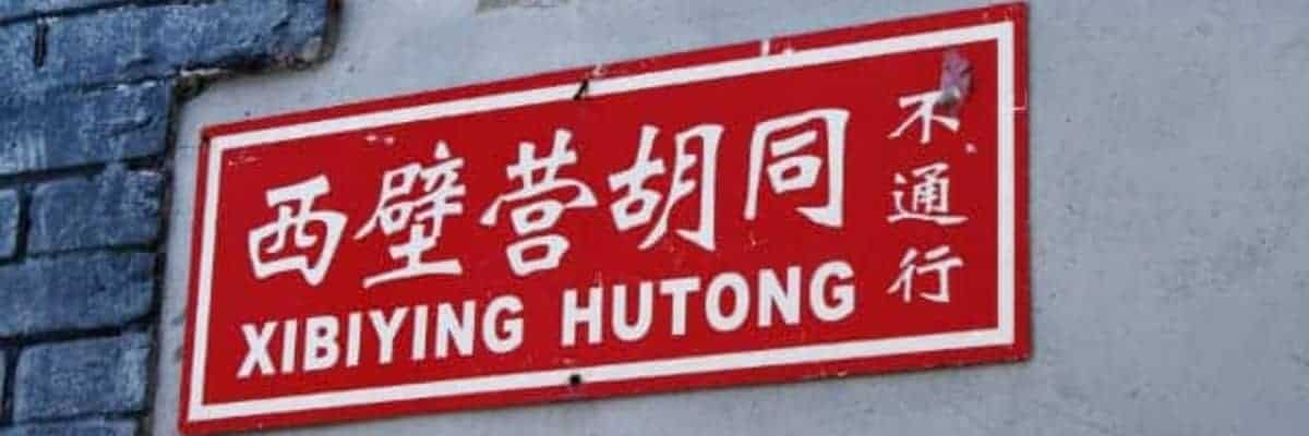 Un letrero rojo con escritura blanca para un Hutong en China
