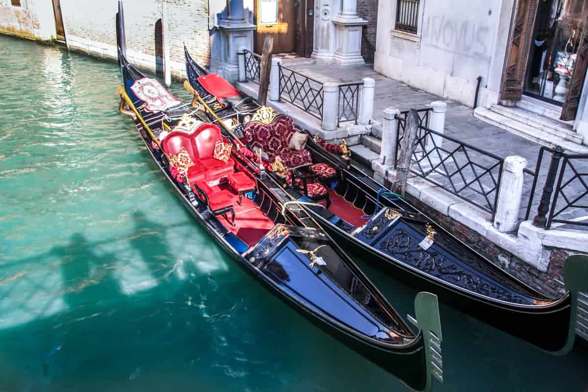 Two lavishly decorated gondolas docked outside a house in Venice