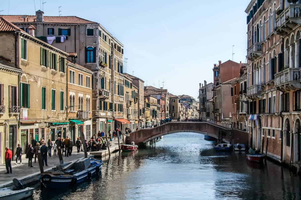 A small Venice canal lined with buildings on either side and cut by small bridges