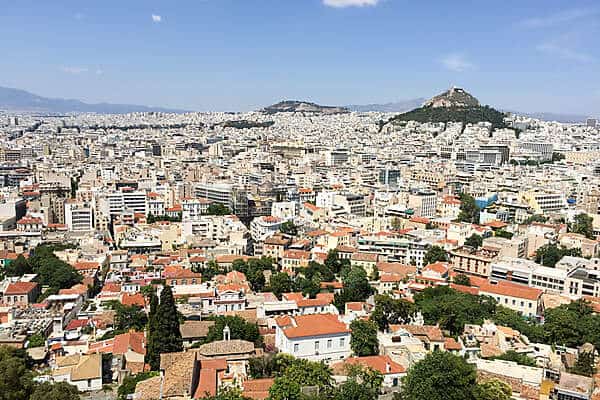 View over Athens with the dense cluster of old houses and apartments buildings in front of, and surrounding, two hills. 