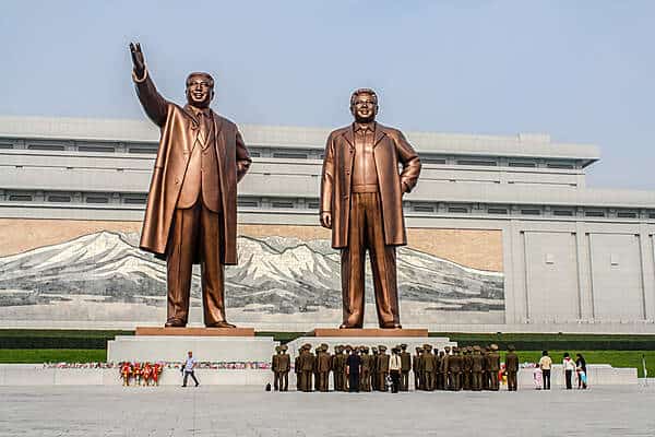 People line up in front of two bronze statues of the Kims in North Korea.
