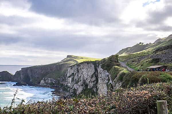 People on a pathways through forested hills upon steep cliffs next to the sea in Northern Ireland. 