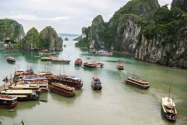 A cluster of wooden double decker boats in the calm rock formation filled waters of Halong Bay in Vietnam. 