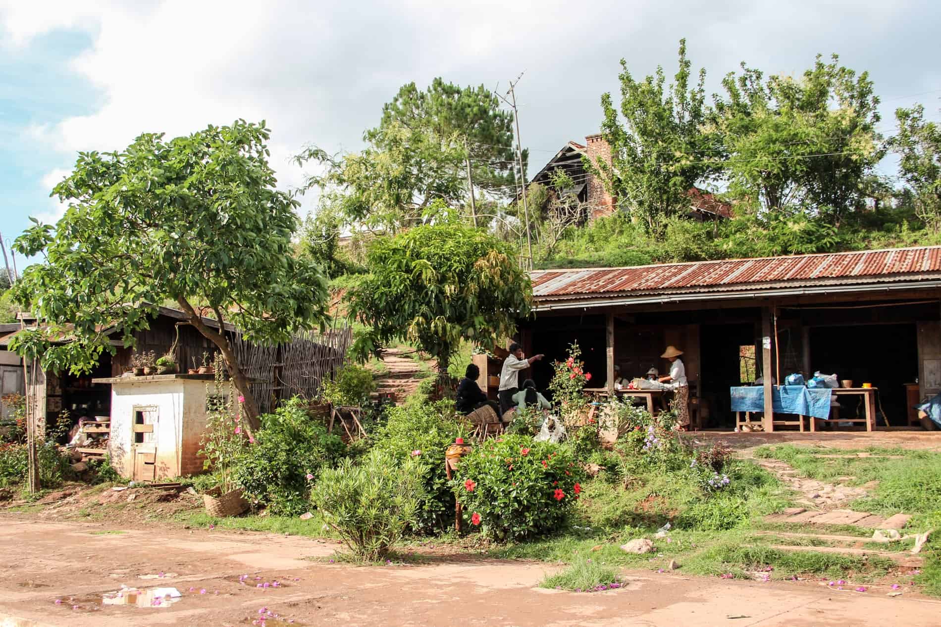 People gathered in the porch of long hut in thick vegetation on Dong Deng island, Laos. 