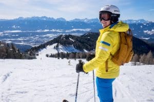 A woman in yellow and blue ski gear standing at the top of a long ski run on the Gerlitzen Alpe in Carinthia, Austria