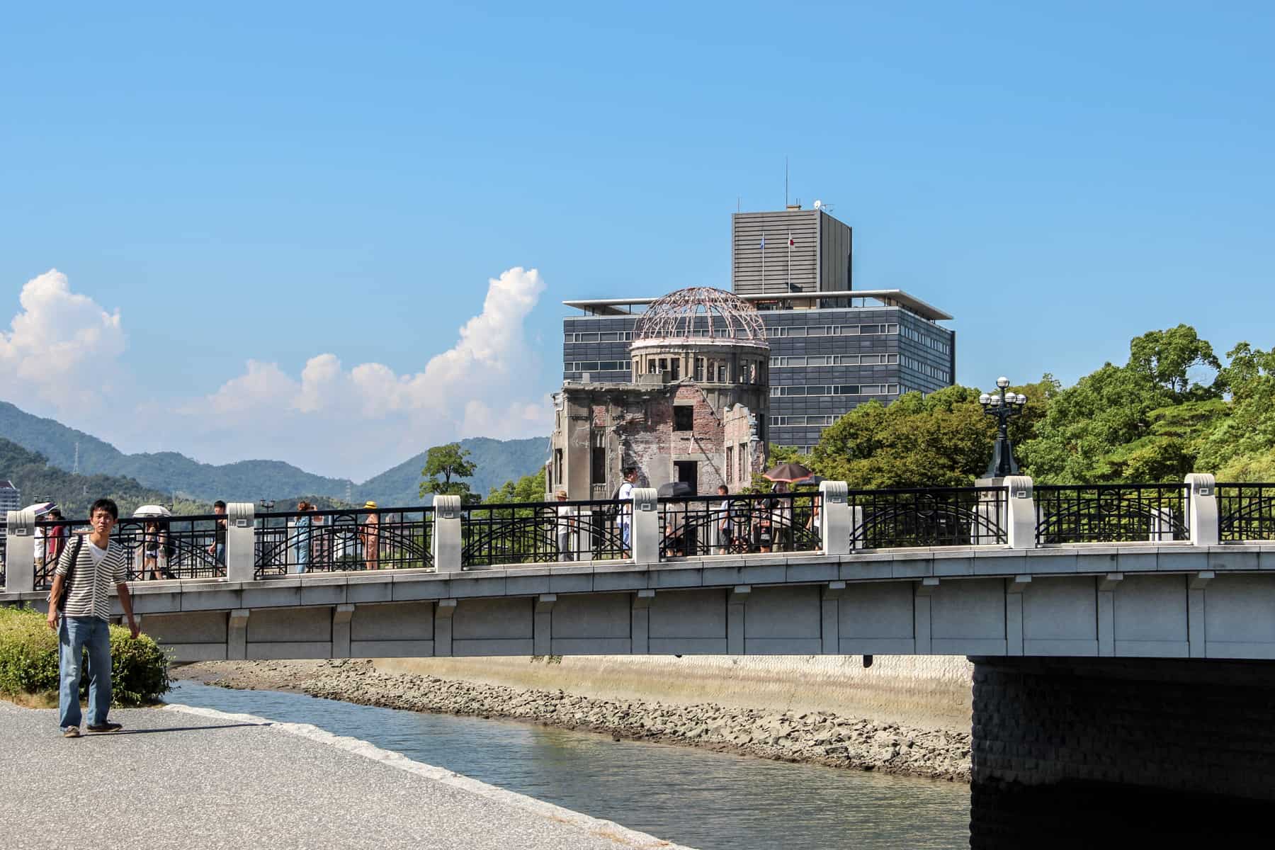 People walking over the river bridge in from of the A-Bomb Dome in Hiroshima's Peace Park Memorial.
