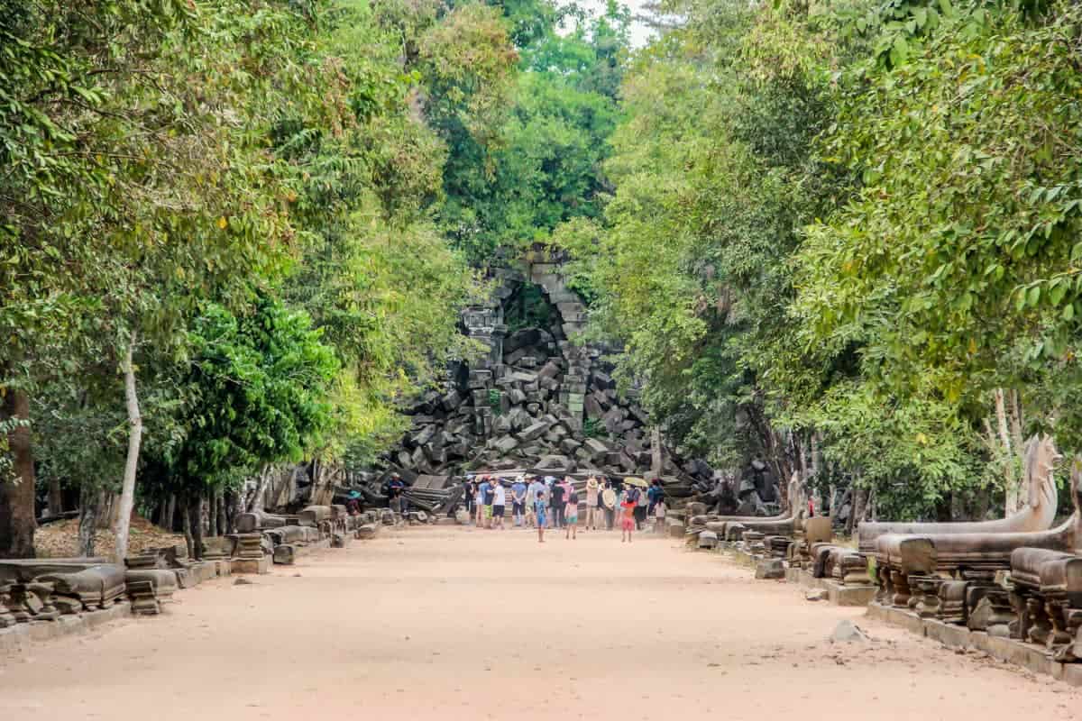El arco en forma de diamante al templo de Beng Mealea bloqueado por pilas de piedras caídas de la estructura y cubierto por el follaje de la selva