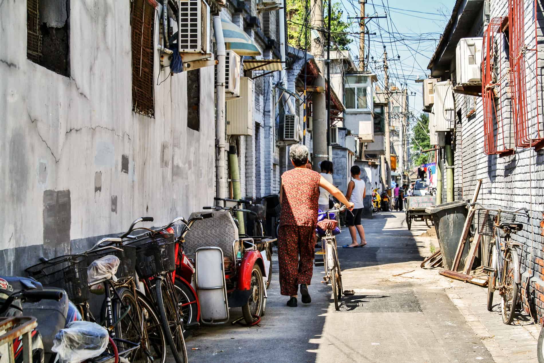 A woman with her bicycle, walking down a Huting street in Beijing. 