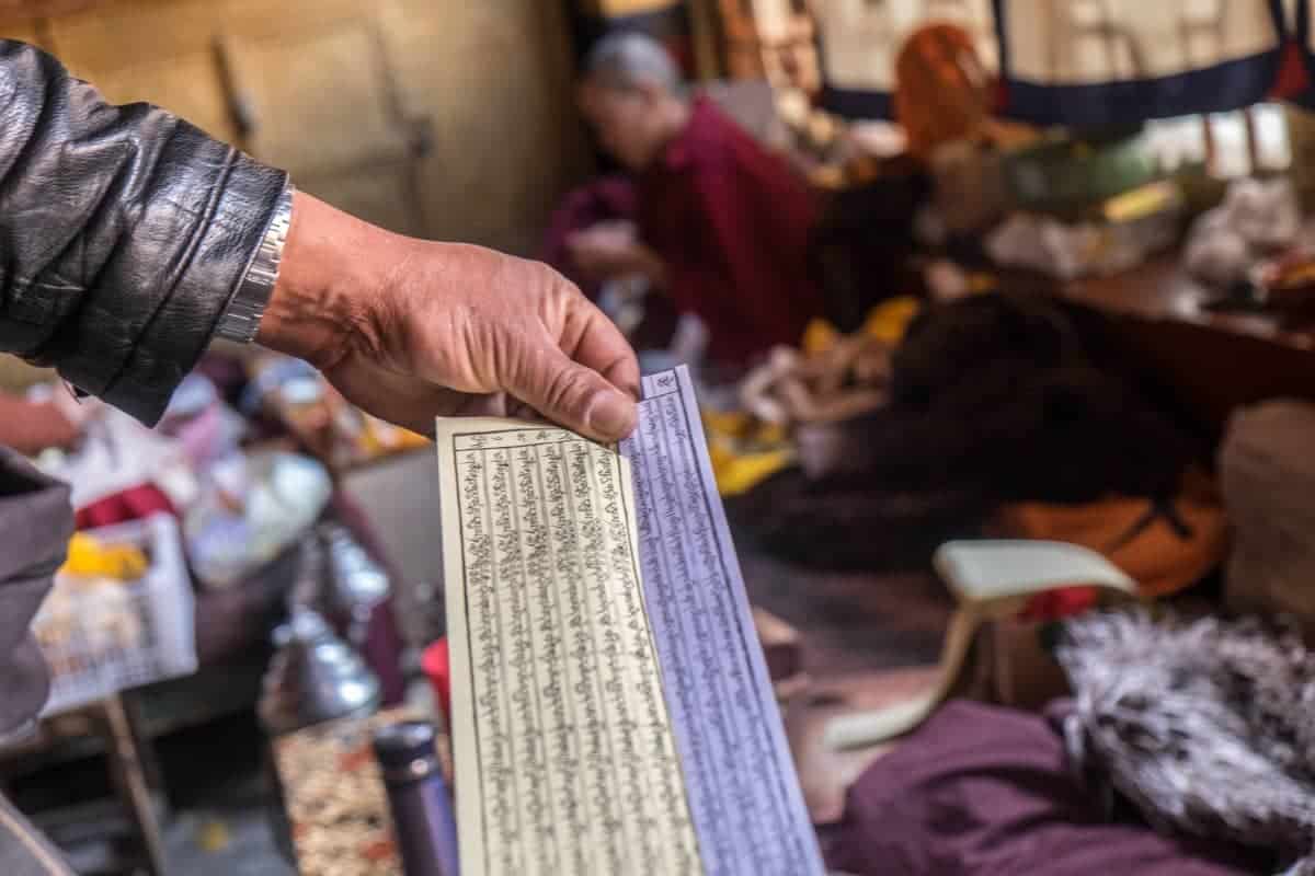 Hombre sosteniendo un papel de oración budista tibetano desenrollado en un convento de monjas en Lhasa, Tíbet 