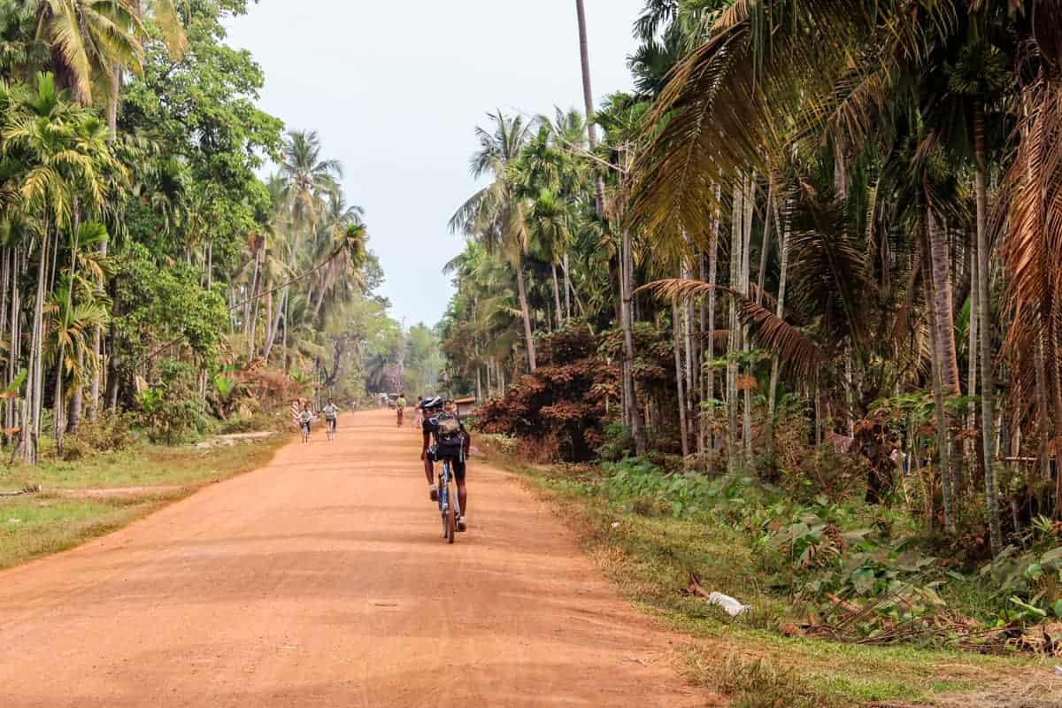 Un guía en bicicleta de Siem Reap en el camino del pueblo polvoriento naranja al templo de Beng Mealea