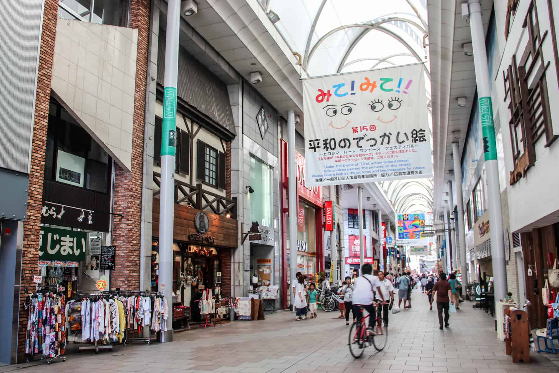 A covered shopping street in Hiroshima city with hanging artworks made by children. 