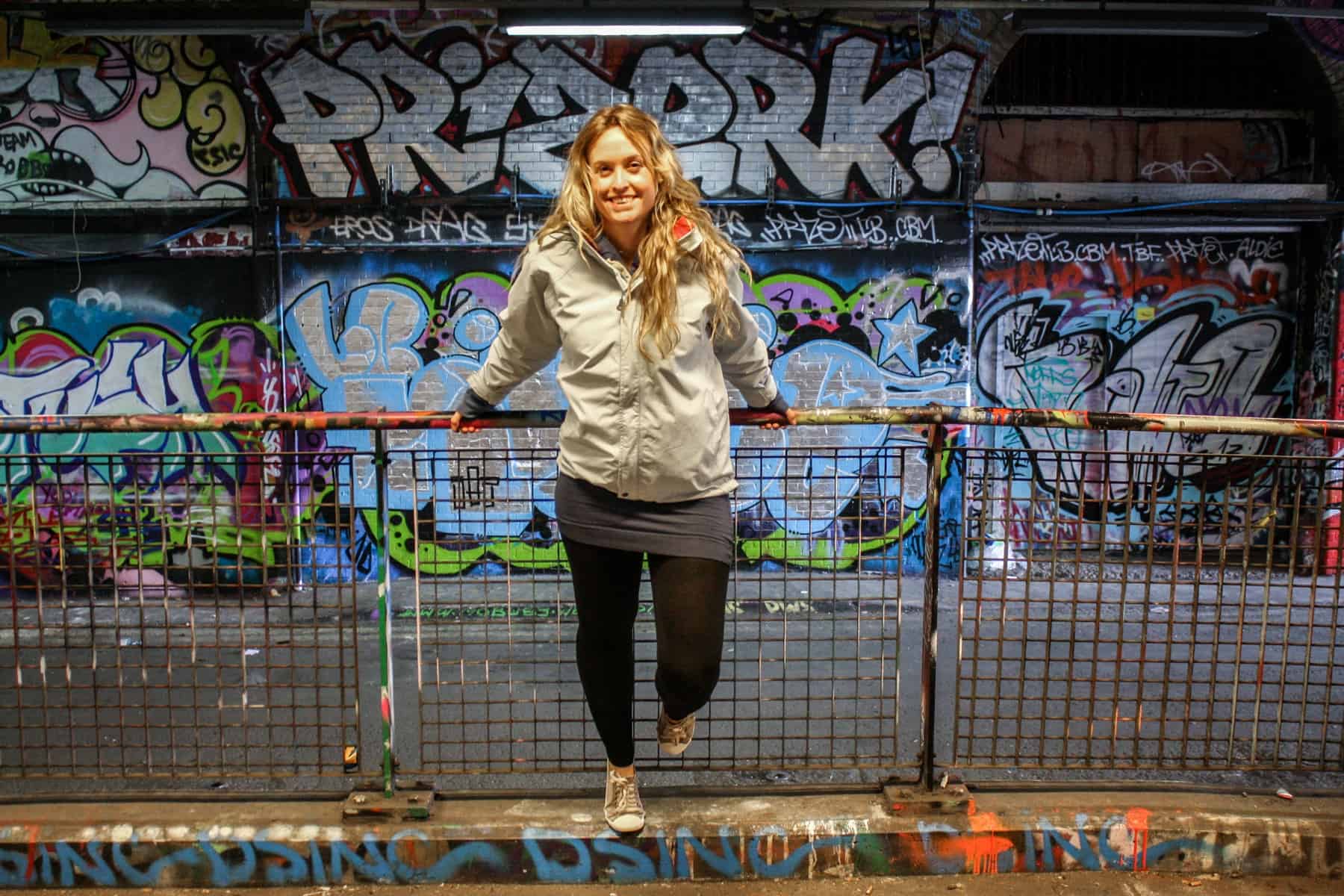 A woman leans on a railing inside the London Graffiti Tunnel. 