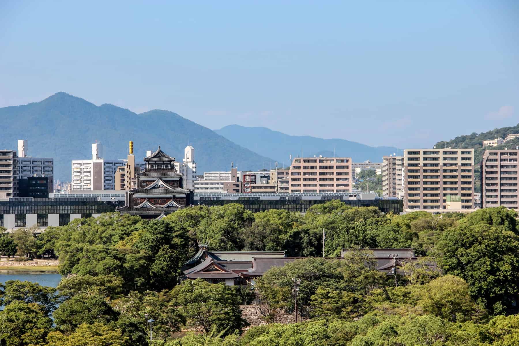 Hiroshima Castle and Shukkei-en Garden in front of the city's more modern skyline and distant hills. 
