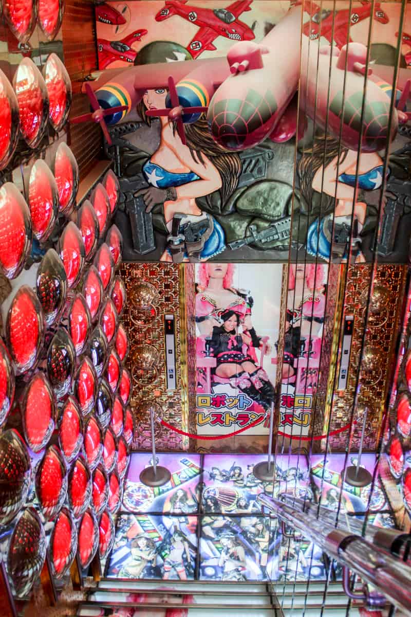 A stairway with red light covered walls and floor to ceilings images of female figures, at the Robot show in Tokyo. 