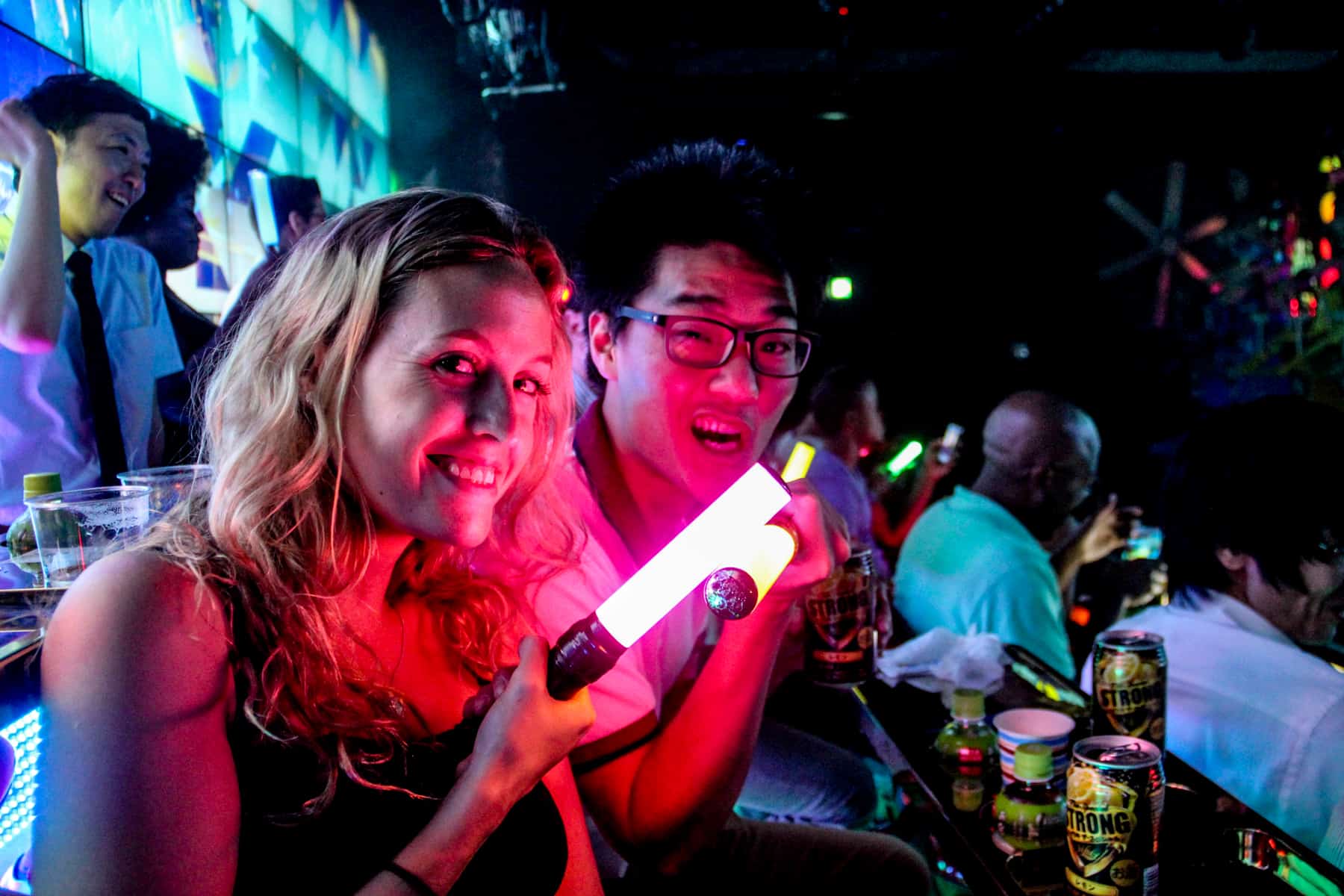 A man and woman with glow sticks, sitting the audience of the Robot show in Tokyo. 