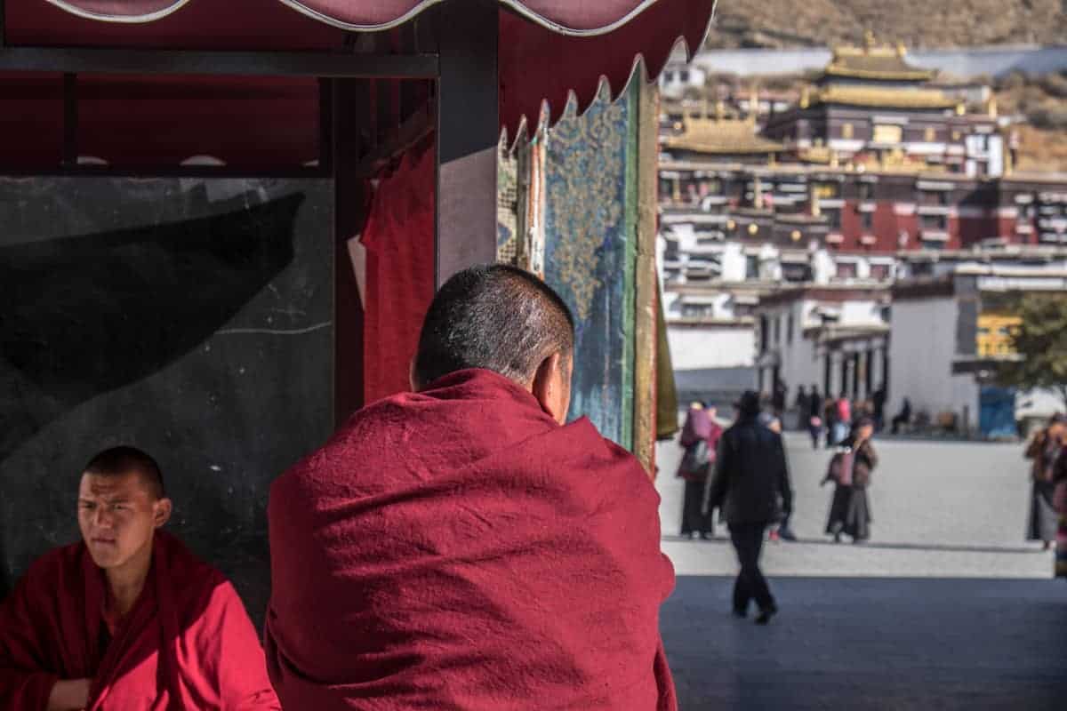 The back of a monk sitting outside the entrance to the Tashi Lhunpo Monastery in Shigatse, Tibet.