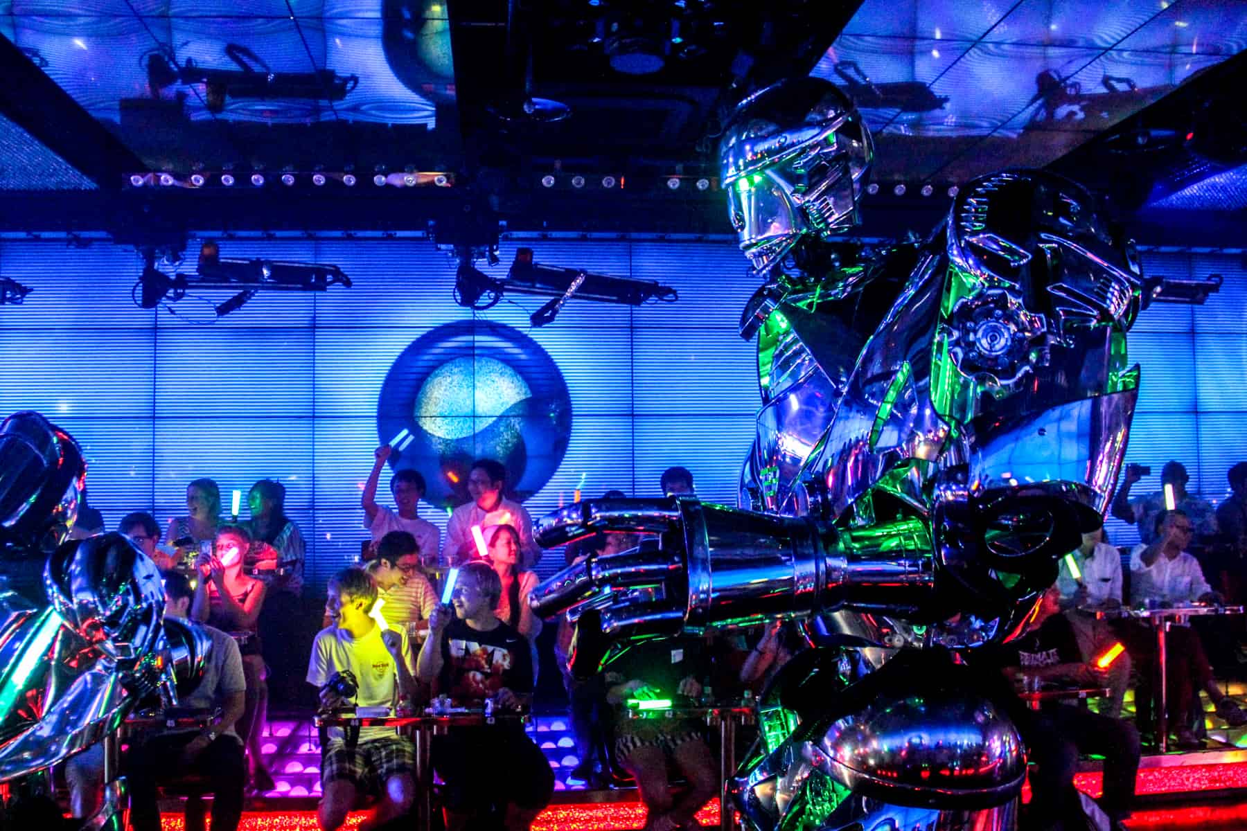 An audience waves neon glow sticks while watching a giant robot perform at a show in Tokyo. 