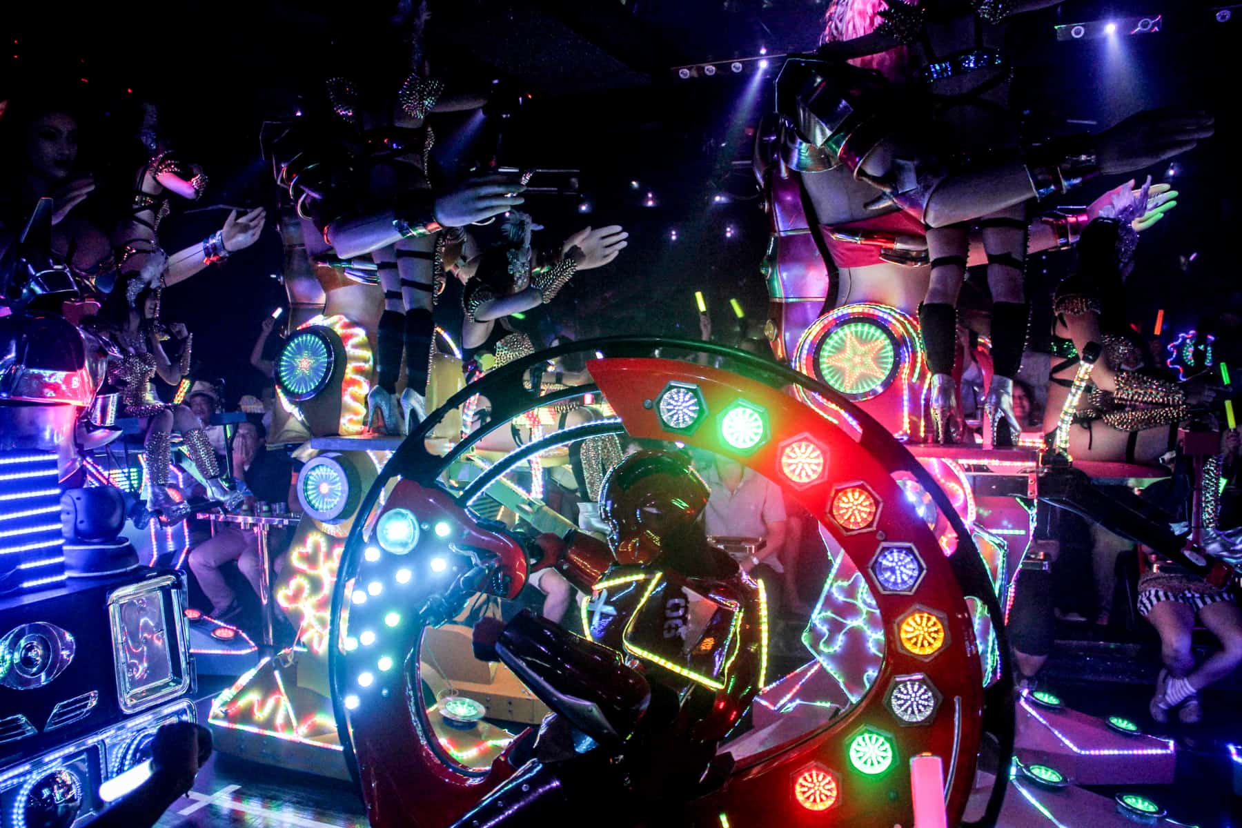A robot in a circular car rides past three tall feminine robots at the Robot Restaurant show in Tokyo. 