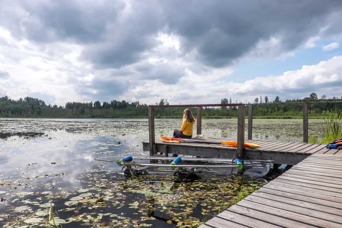 Mujer sentada junto al tranquilo lago Ergli en la naturaleza de Letonia 