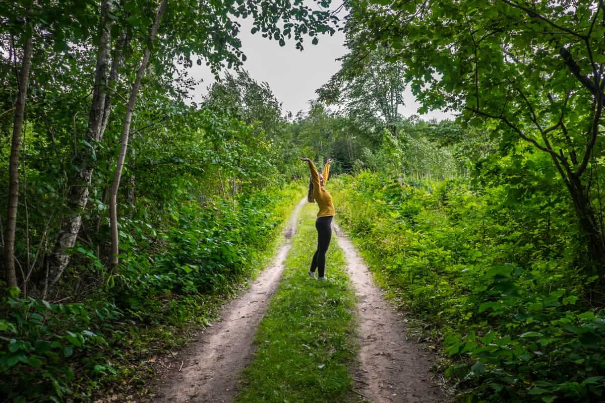 Mujer caminando y bailando en la naturaleza de Letonia en senderos del campo de Ergli