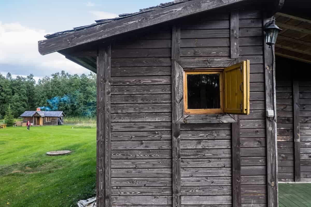 Wooden hut accommodation with a traditional Latvian bathhouse in the backgound at a campsite in Gauja National Park in Latvia