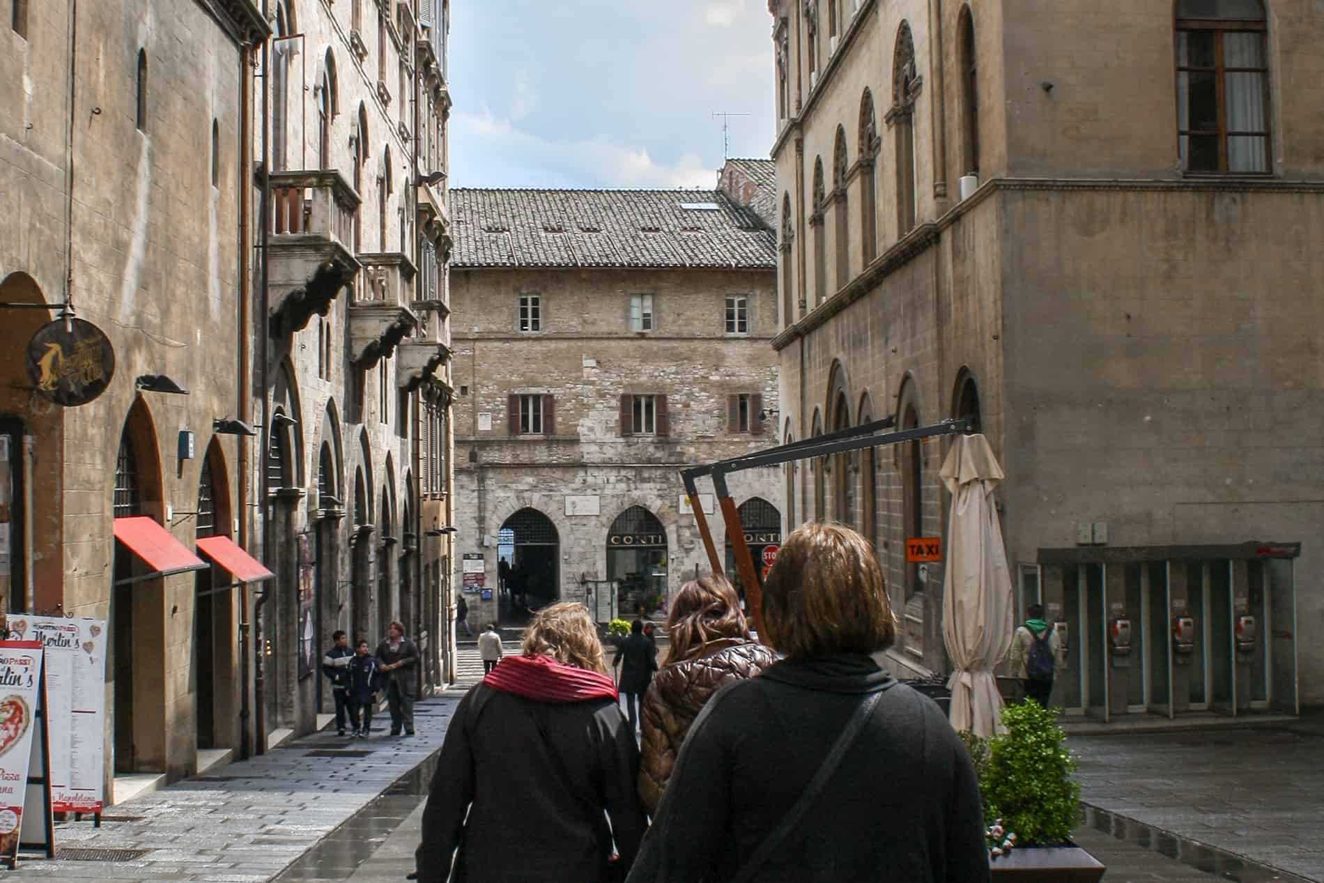 A small group of visitors Perugia sightseeing in the city's old sandy stone streets. 
