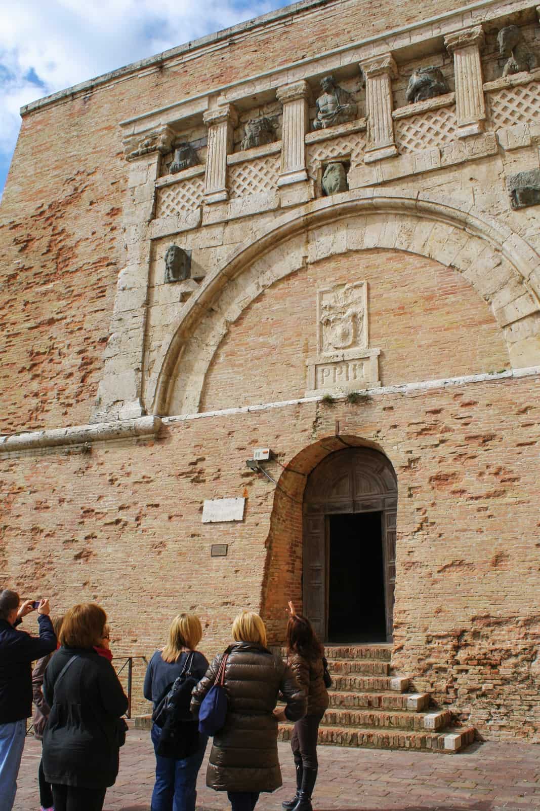 A tour group looking up to the stone archway on the golden brick Rocca Paolina Fortress in Perugia, Italy. 
