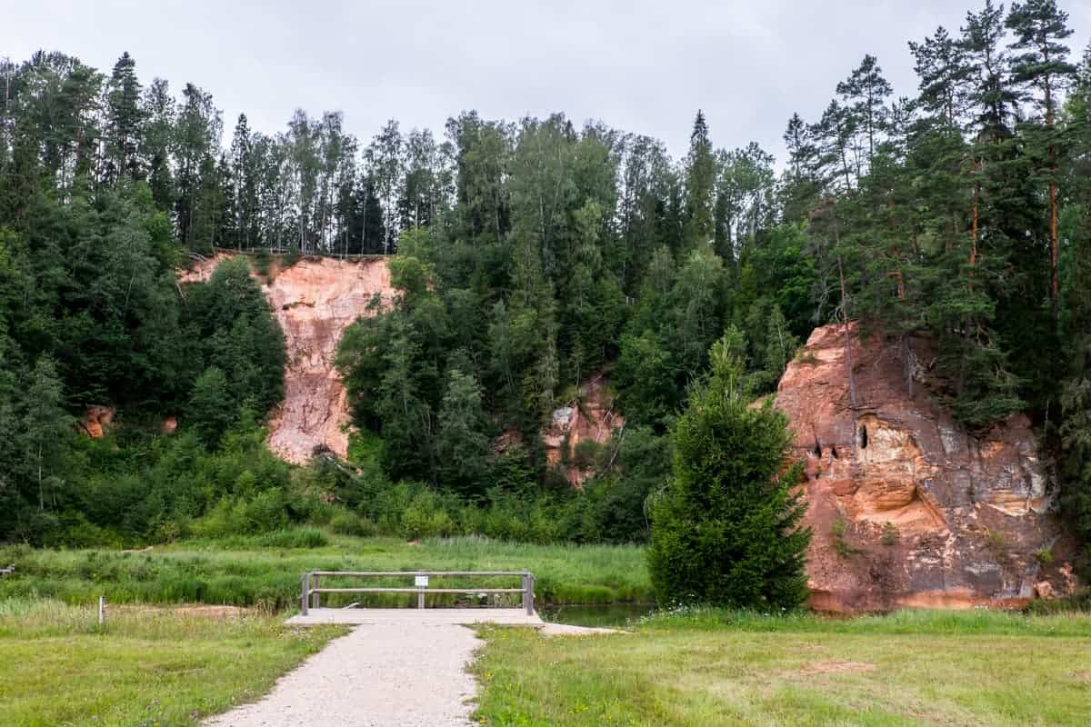 The orange facade of Zvartes Rock covered by forest in in Gauja National Park Latvia