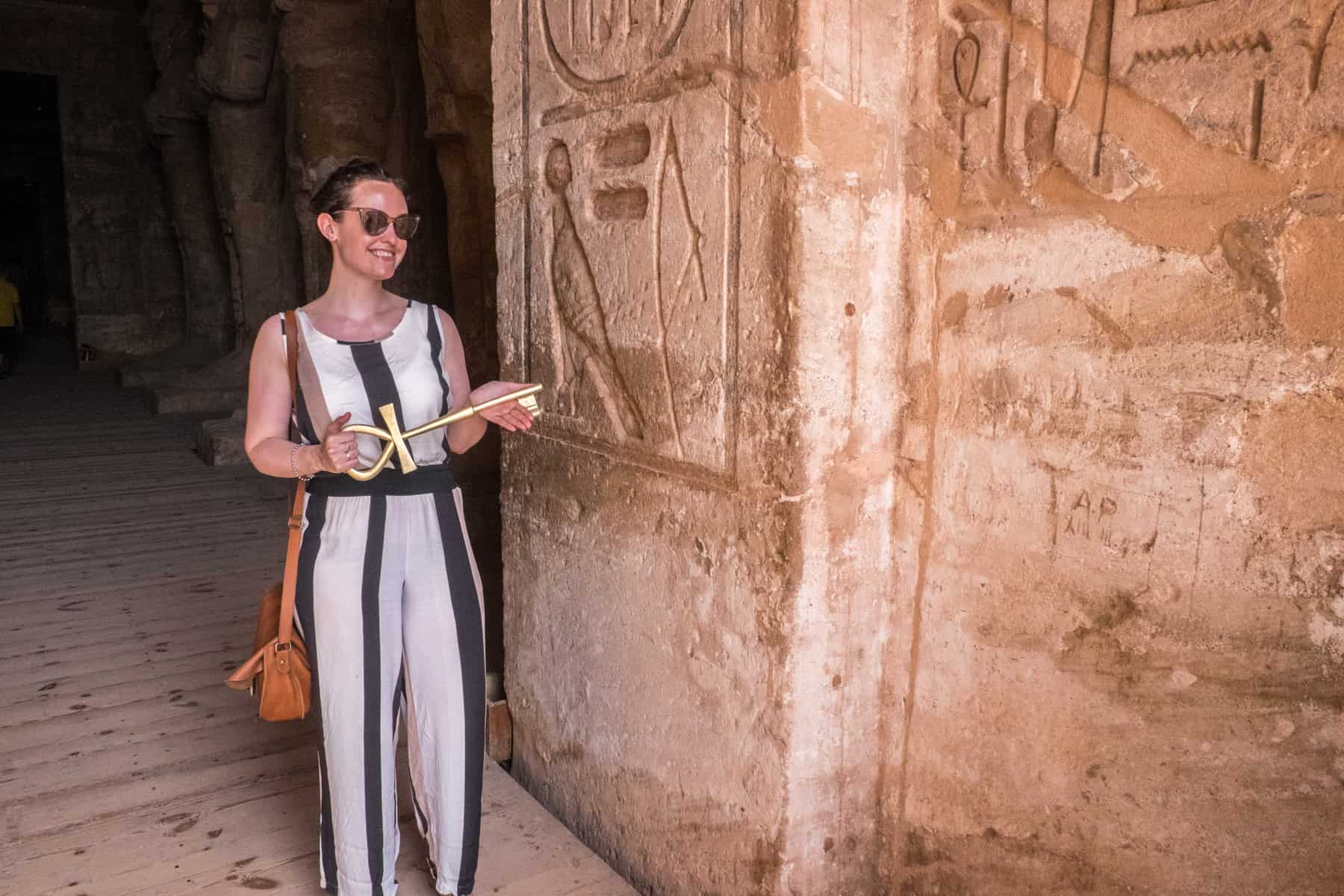 A woman holds a giant Ankh (Ancient Egyptian symbol of life) key at the entrance door to the Abu Simbel Temple in Egypt