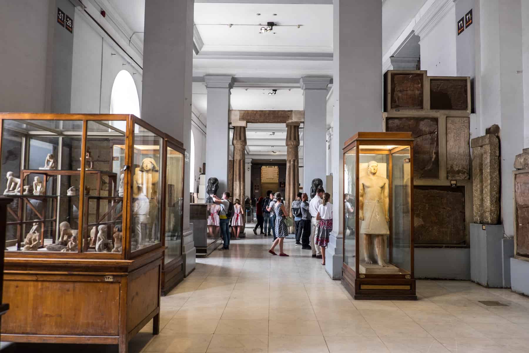 Artefacts in Large wooden and glass exhibits line the tall, wide corridors of the Egyptian Museum in Cairo Egypt