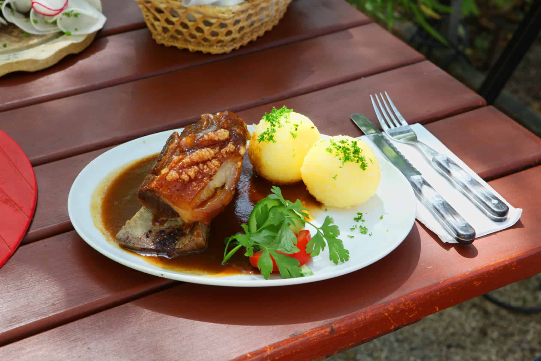 El plato de carne de paleta de cerdo conocido como Fränkisches Schäufele en Nuremberg, se sirve con dos albóndigas de papa, salsa y una guarnición de ensalada roja y verde.
