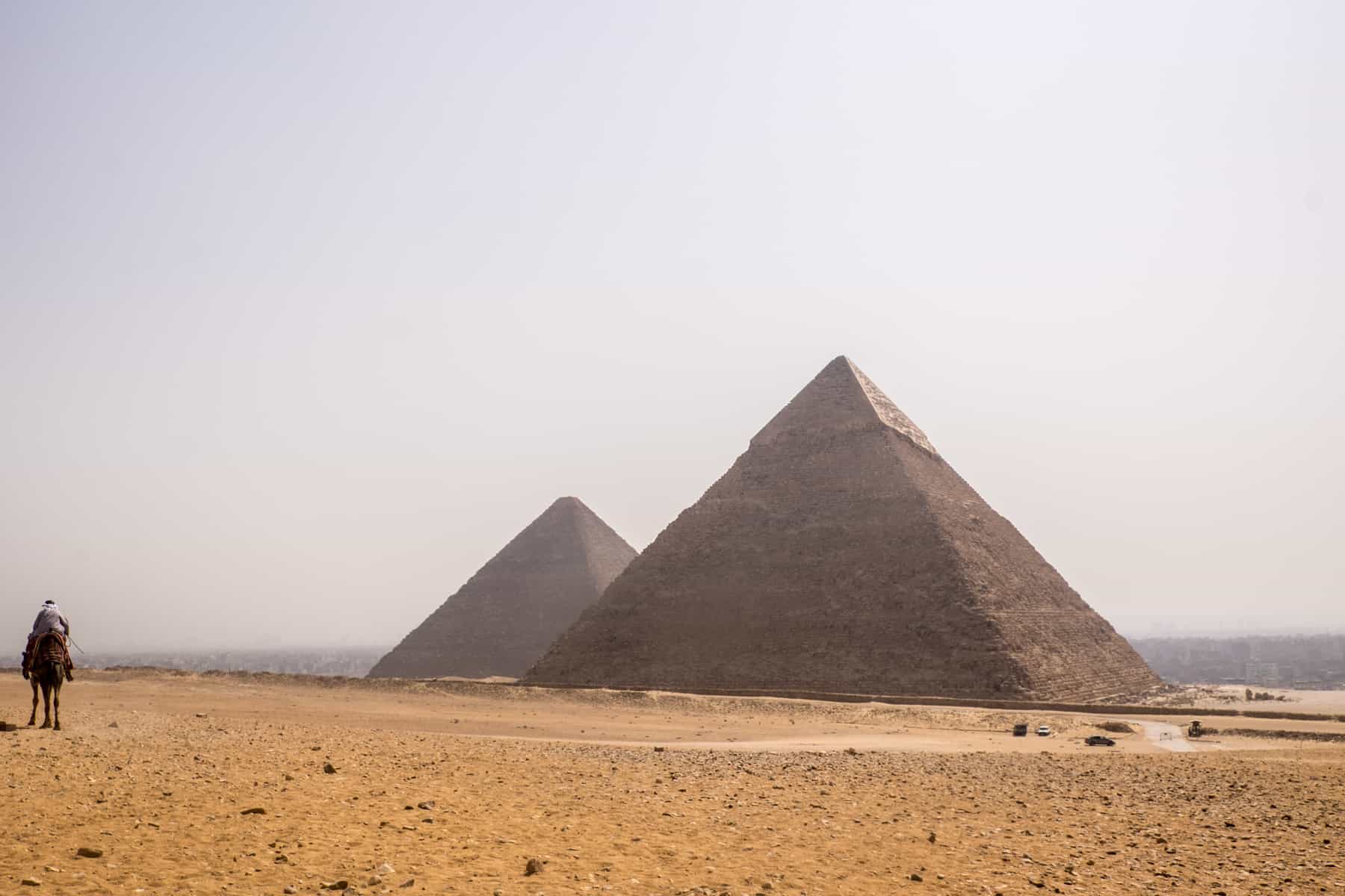 The great and middle pyramids of Egypt stand out in the desert of Giza, blocked out the city skyline in the distance