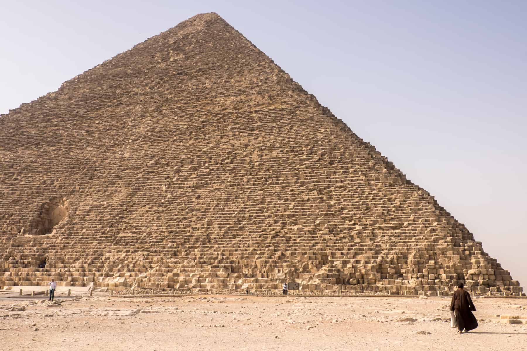A man looks tiny in front of the Great Pyramid in Giza, Egypt made of 2.5 millions stones