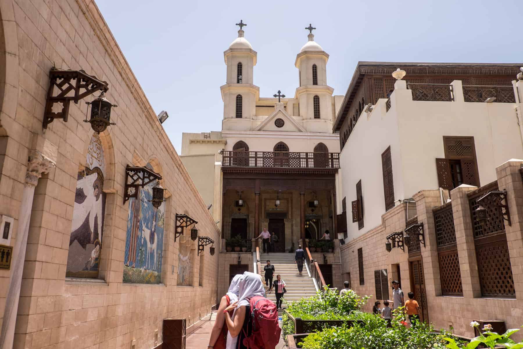 Tourists in headscarves approach the steps leading to the entrance of the Hanging Church in Cairo, Egypt