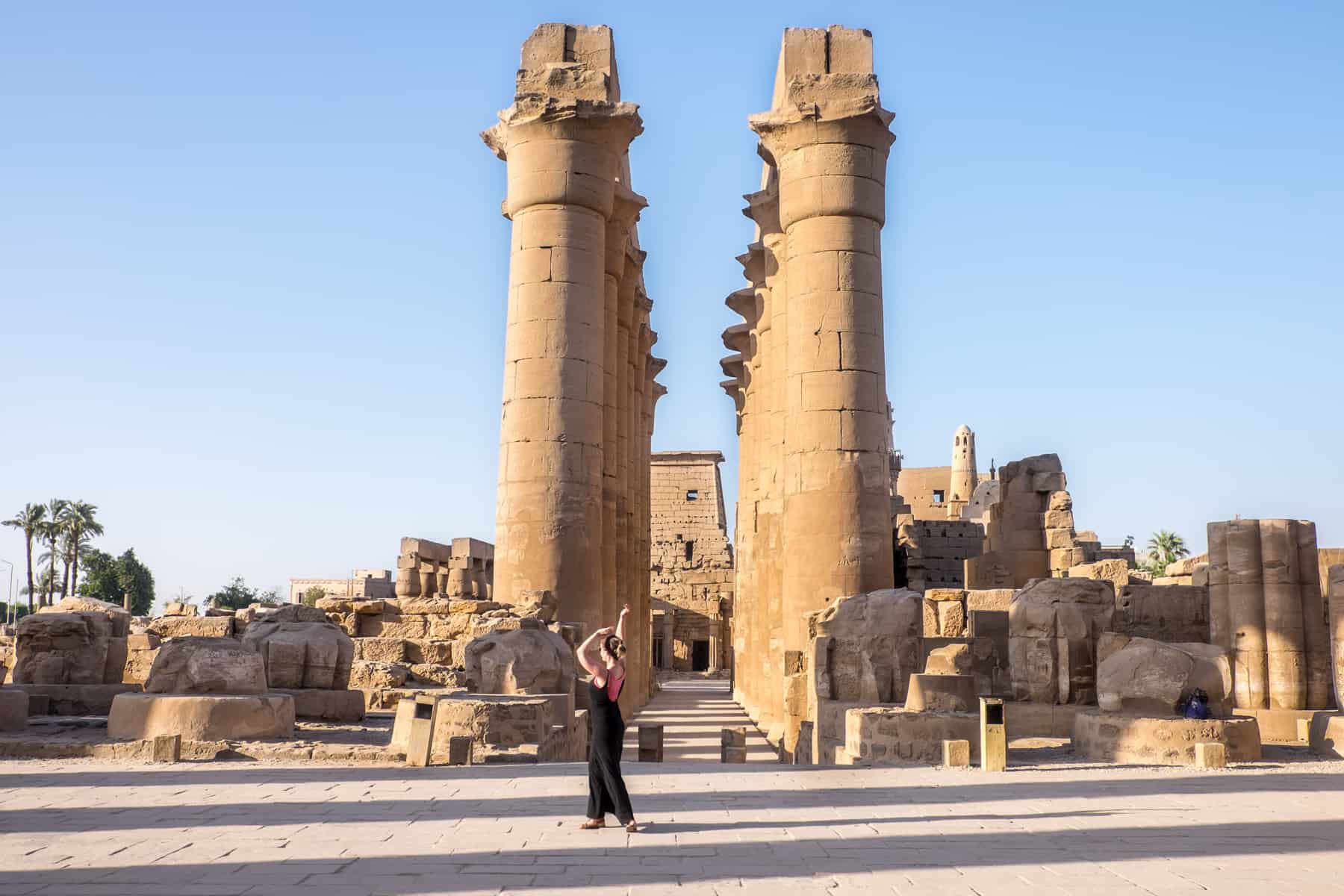 A woman dances in front of a row of tall columns at the Luxor Temple site in Egypt