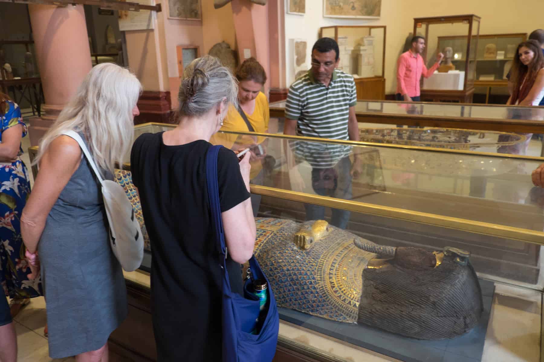 Tourists look at an Egyptian Mummy coffin in a glass case in the Egyptian Museum in Cairo, Egypt