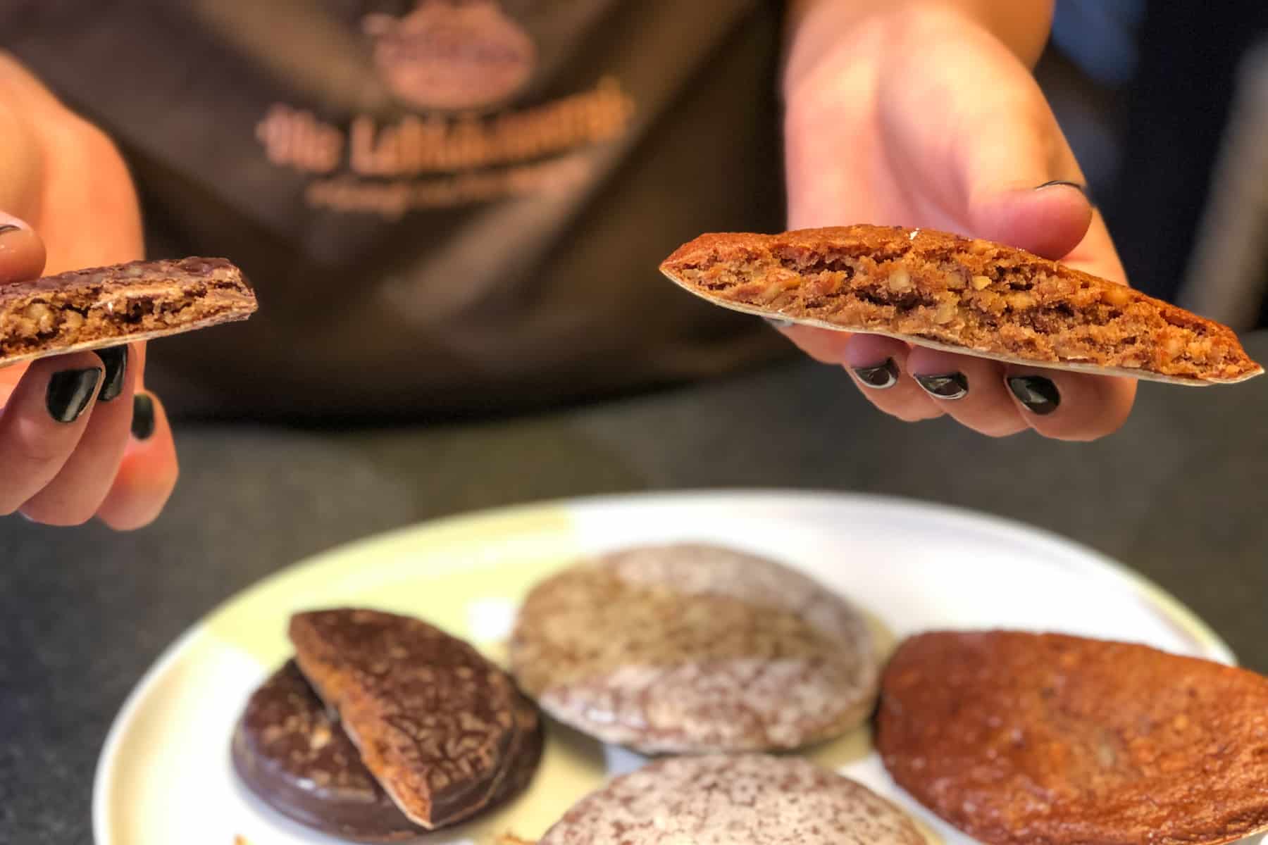 Los mejores lugares para Comer y Beber en Nuremberg Un par de manos sostiene un pan de jengibre de Nuremberg partido por la mitad para mostrar la mezcla de nueces en el interior y cómo se hace