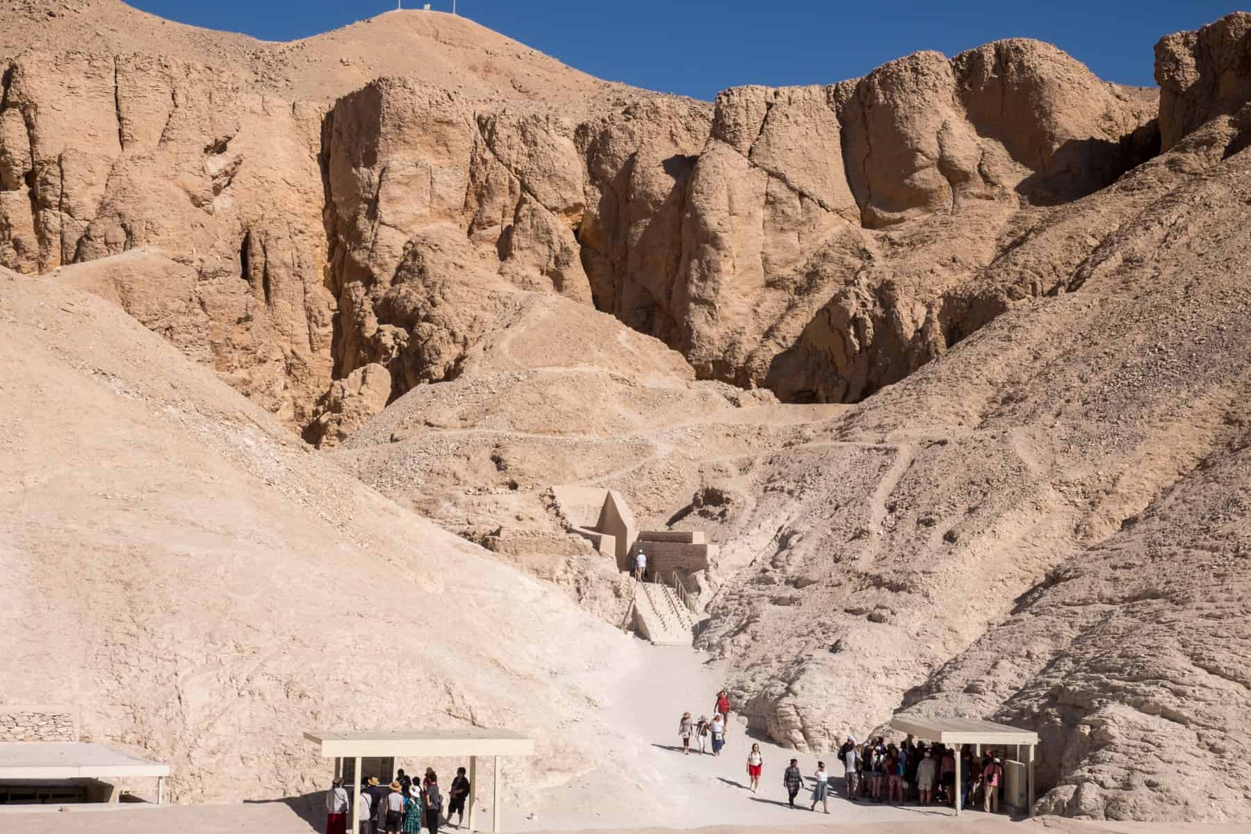Tourists enter the small doors built into the Luxor mountain rocks at the Valley of the Kings - one of the best place to visit in Egypt