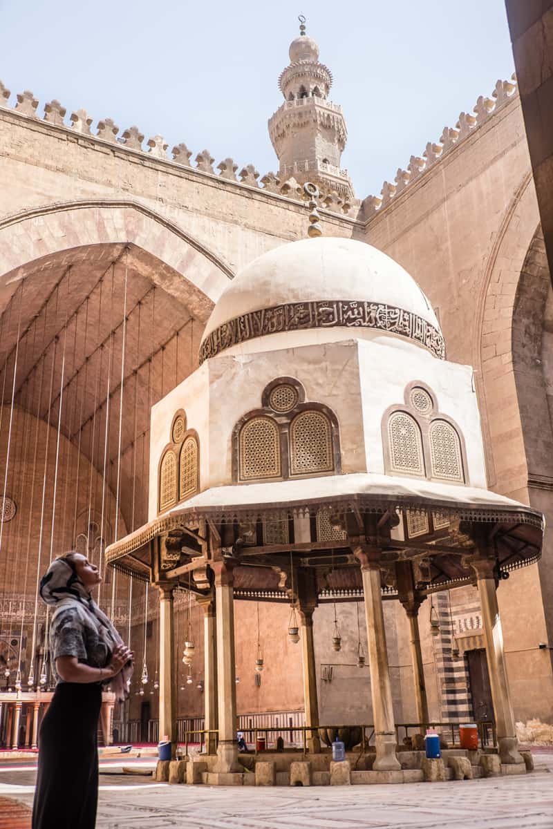 A woman stands within the large courtyard of the Sultan Hassan Mosque in Cairo, Egypt
