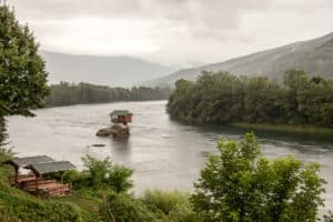 A tiny House on the River Drina in Serbia, perched on a rock in the middle of the water, surrounded by forest.
