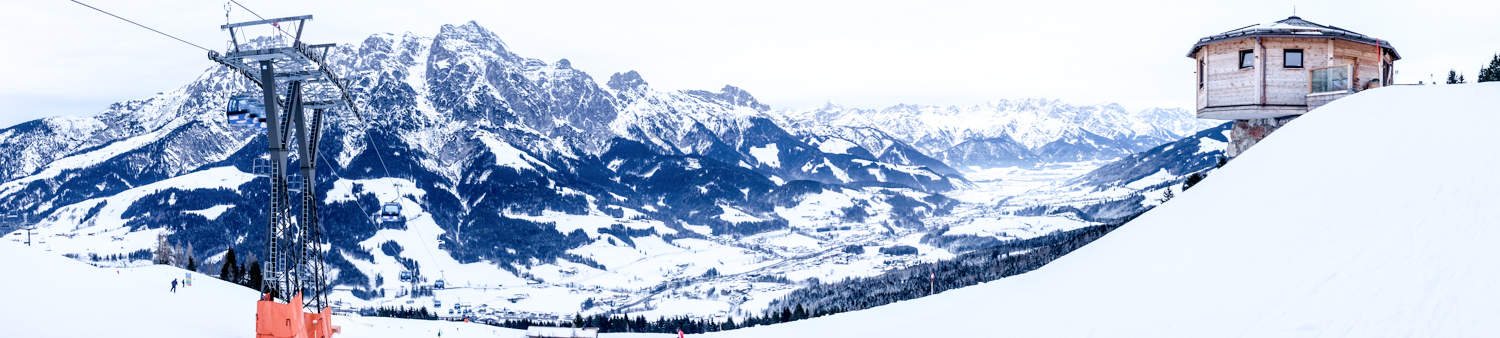 A panoramic image of the skicircus ski resort in Salzburg Austria, showing the cable cars, mountain huts, valley beds and mountains