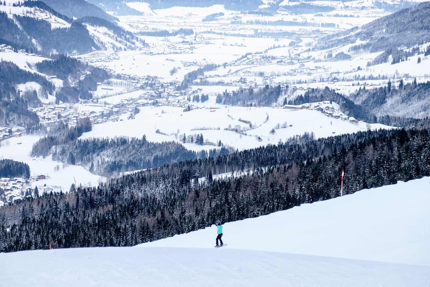 A lone skier on the slopes of a Salzburg ski resort with the valley bed below in the background