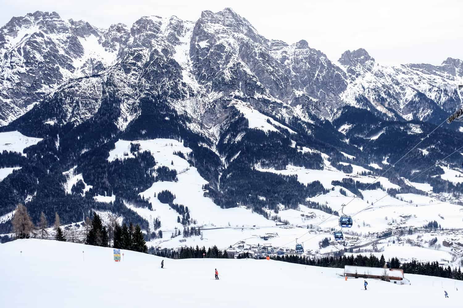 People skiing on the thick snow covered Salzburg ski resort known as skicircus with the looming Salzburg mountains in the background