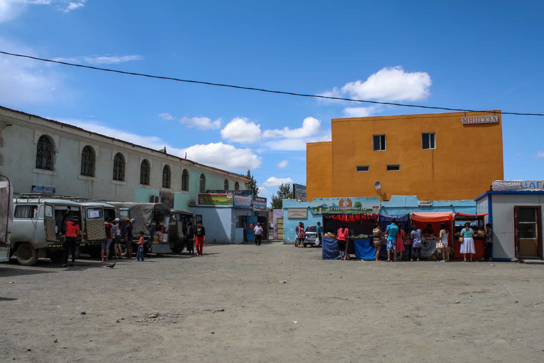 People gather in a courtyard surrounded by colourful buildings in the town of Dalanzagad, Mongolia