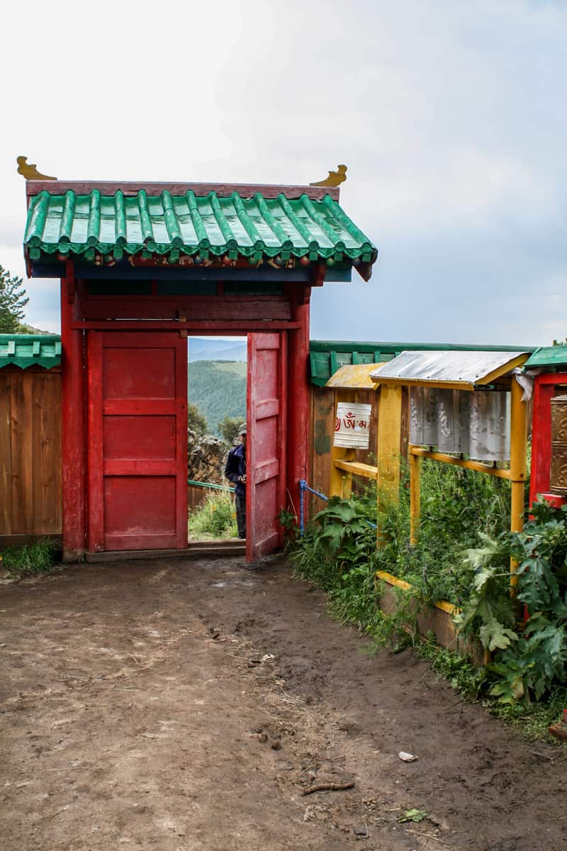Una puerta roja con techo verde menta marca la entrada al monasterio Tövkhön de Mongolia