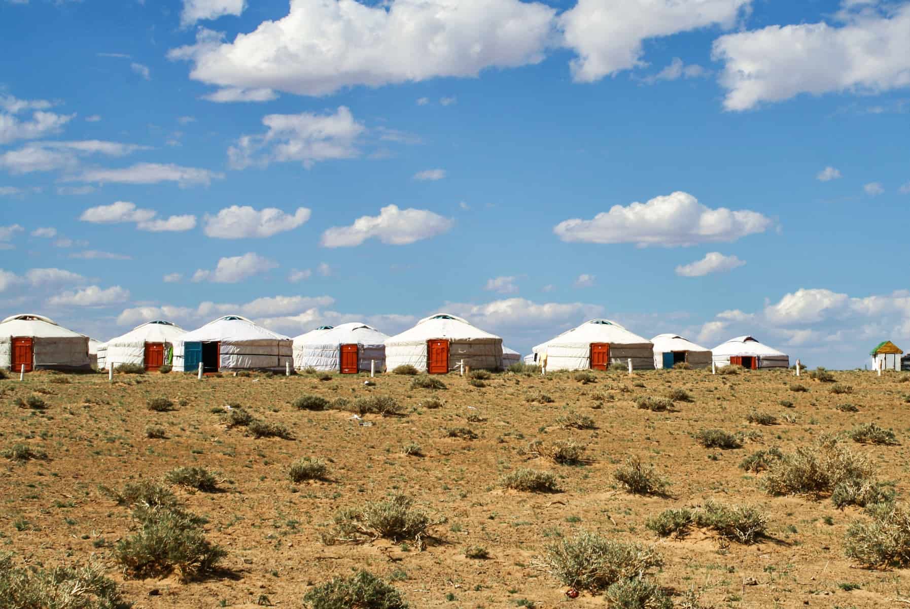 Una docena de gers blancos se alinean en la cima de una colina en el desierto de Gobi, Mongolia