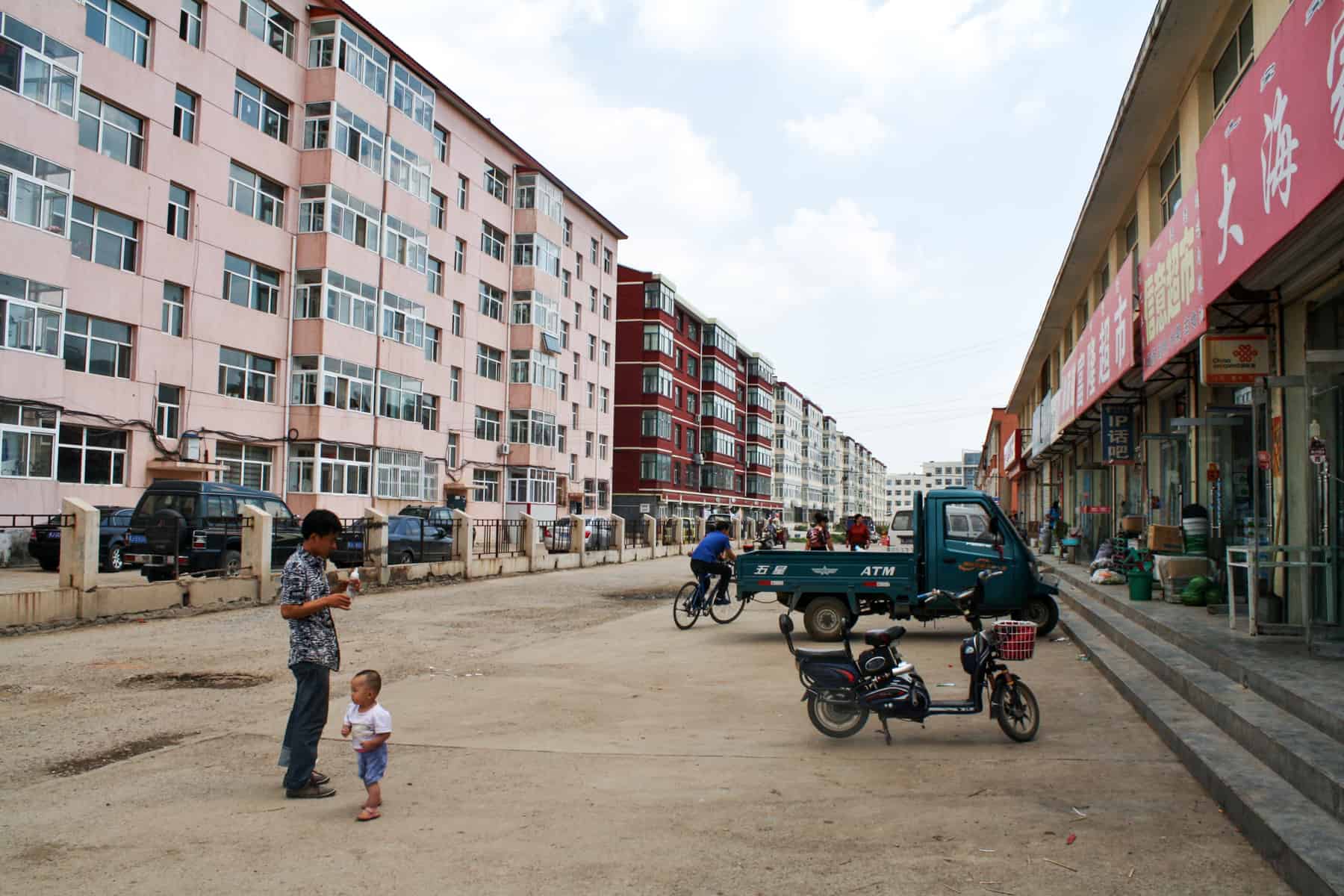 Un hombre y un niño en la calle de una calle bordeada de apartamentos en una ciudad de Mongolia Interior, China