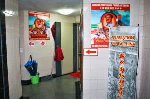 Basement corridor with white tiled walls covered with Chairman Mao posters and red arrows pointing to the Shanghai Propaganda Poster Art Centre