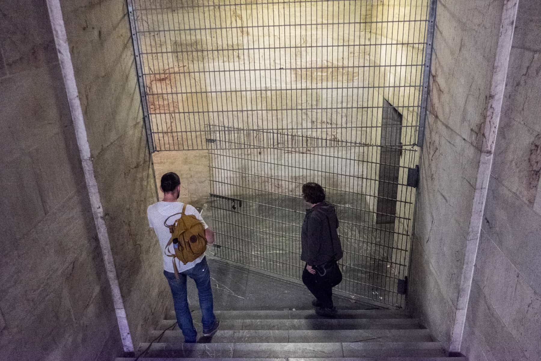 A man and a female tour guide walk through the looming marble interior of the Zeppelin Field Tribune building - one of the Nazi Party Rally Grounds sites